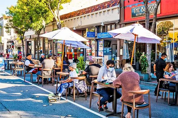 Customers eating at outdoor tables on a busy main street