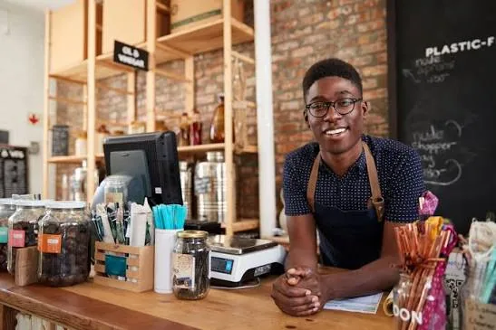 A shop owner smiling behind his counter